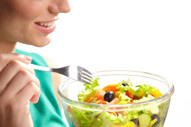 野菜のサラダだけで栄養不足の食事をする女性の写真