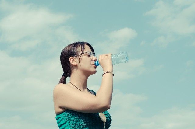 水分不足を水を飲んで補う女性の写真