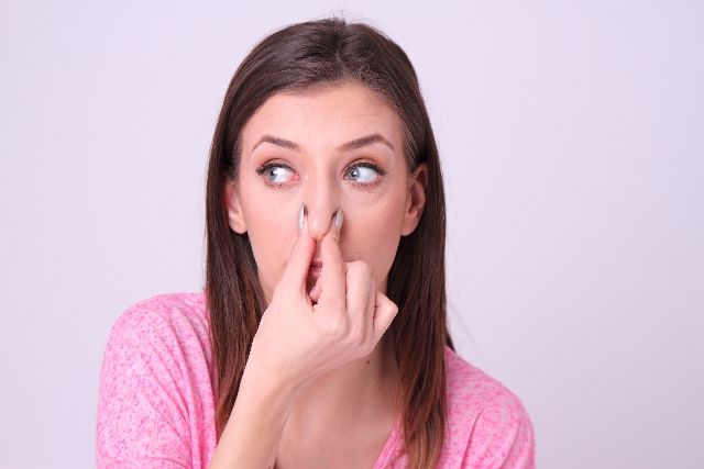 口臭の原因を知って鼻をつまむ女性の写真